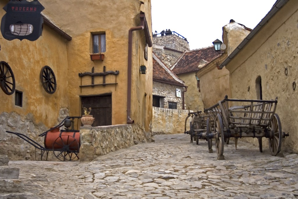 Medieval street inside Râșnov Fortress with wooden cart and cobblestones, Transylvania Romania.