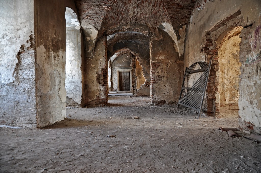 A ruined vaulted interior room of Bánffy Castle, with exposed brick and crumbling plaster
