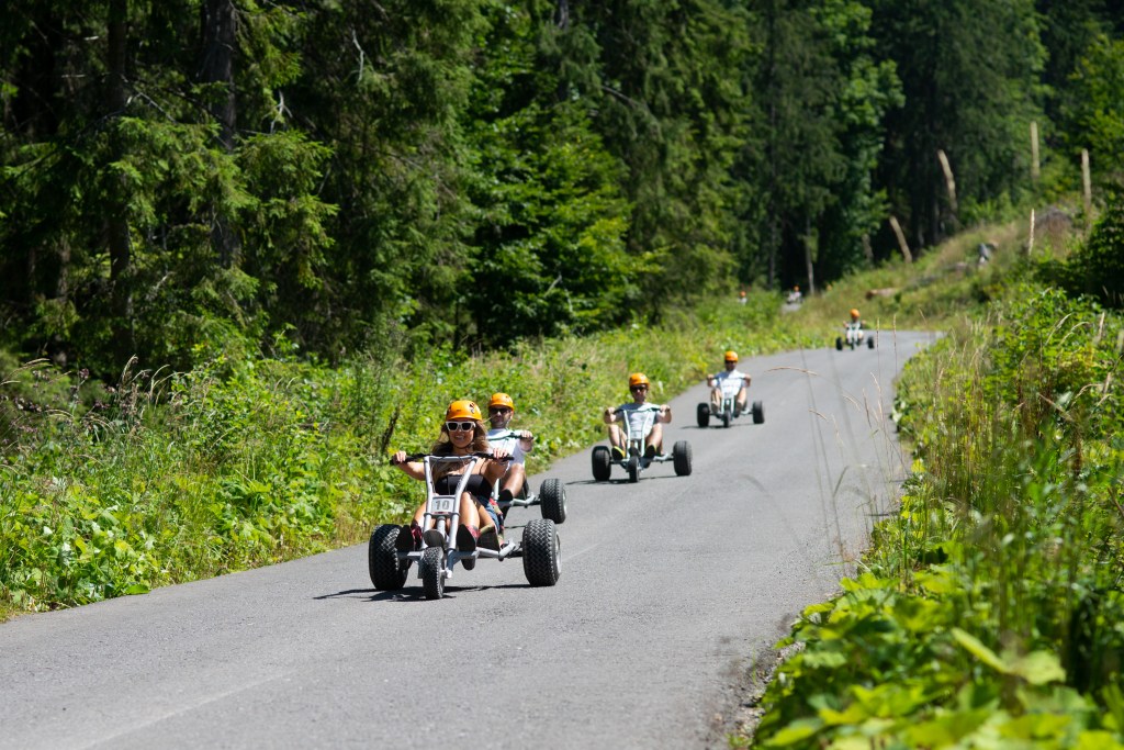 Visitors riding mountain karts down a forest road near Băile Tușnad.