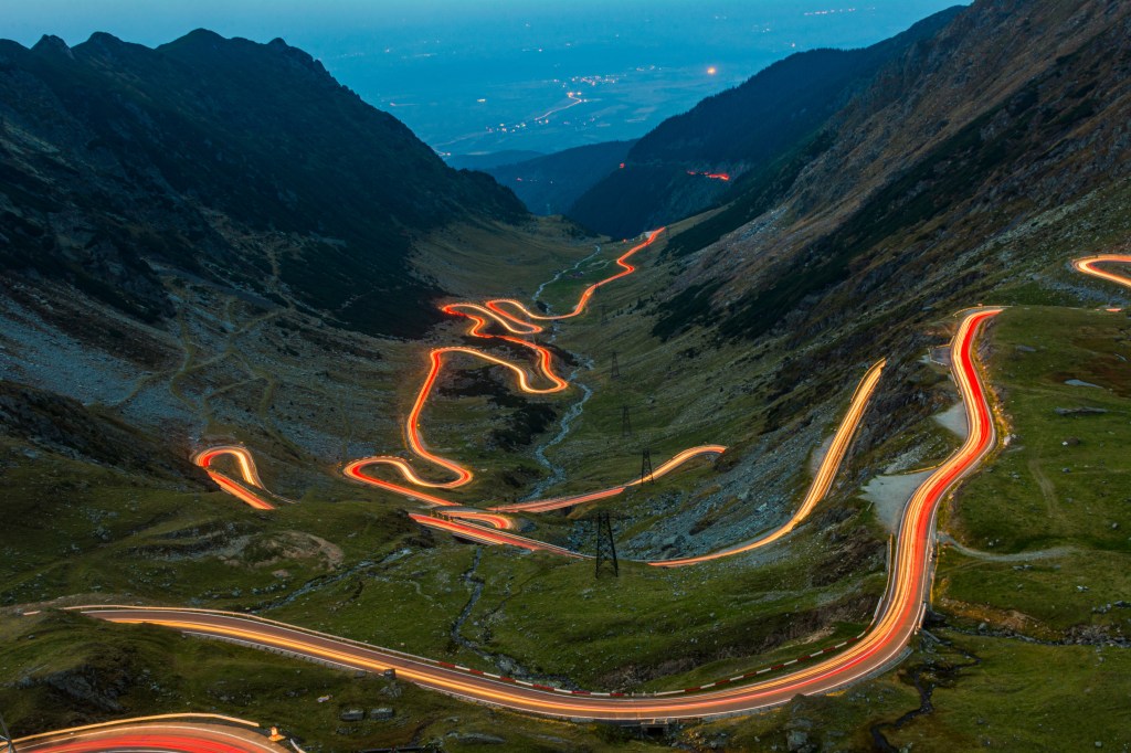 Light trails from cars at night on the Transfăgărășan, winding through the Carpathian mountains.